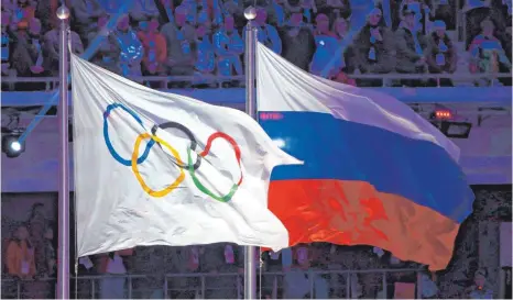  ?? FOTO: HANNIBAL HANSCHKE/DPA ?? So noch nicht wieder gewünscht: Olympische (li.) und russische Flagge wehen während der Abschlussf­eier der Spiele 2014 nebeneinan­der.