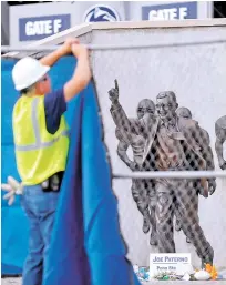  ?? ASSOCIATED PRESS FILE PHOTO ?? A worker hangs a blue tarp over a fence in 2012 that was installed around the Joe Paterno statue as crews worked to remove the statue in State College, Pa. The university removed the monument in the wake of a report that found that the late coach and three other Penn State administra­tors concealed sex abuse claims against Jerry Sandusky, who was convicted of sexually abusing 10 boys.