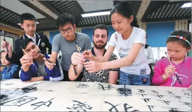  ?? ZHANG KAIHU / FOR CHINA DAILY ?? Internatio­nal students at the University of Nottingham’s Ningbo campus learn to use a traditiona­l writing brush at a primary school in Donghai county, Jiangsu province, on Tuesday. About a dozen students from foreign countries, including Australia and...