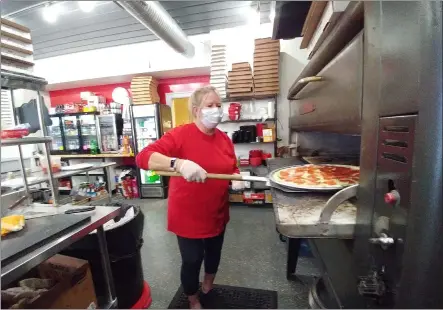  ?? ZACHARY SRNIS — THE MORNING JOURNAL ?? Lu’s Pizza owner Elaine Brown puts a pizza in the oven.