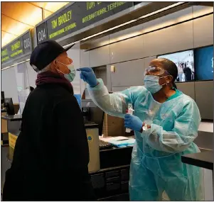  ?? (AP/Jae C. Hong) ?? Caren Williams, a licensed vocational nurse, collects a nasal swab sample from a traveler Monday at a covid-19 testing site at Los Angeles Internatio­nal Airport.