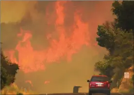  ?? The Associated Press ?? A Santa Barbara County Fire Department vehicle drives along Highway 154 in the Whittier fire east of Cachuma Lake in Santa Barbara County, Calif.