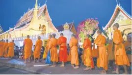  ?? Picture: AFP ?? SIMPLE ACT. Buddhist monks line up at dawn to receive food and alms from devotees in front of a pagoda in Luang Prabang.