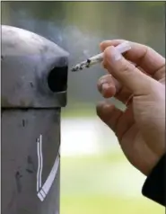  ?? ELAINE THOMPSON - THE ASSOCIATED PRESS ?? A University of Washington student discards a cigarette into a container at a designated smoking location on the campus in Seattle. Seventeen public health schools in the U.S. and Canada have pledged to refuse research money from a new anti-smoking...