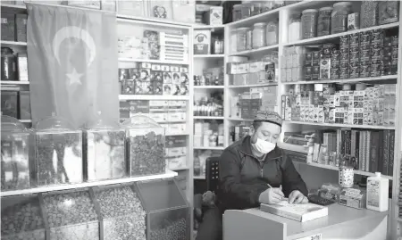  ?? EMRAH GUREL/AP ?? Ahmed Hasim, a member of the Uighur ethnic group, waits for customers Tuesday in his grocery store in Istanbul, Turkey.