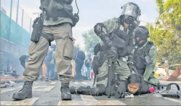  ?? AP ?? A riot police officer detains a student during clashes in Hong Kong while another cop stands guard.