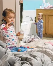  ??  ?? Mazzy, left, and her sister Juniper, 2, brush their teeth before going to bed.