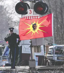  ?? ADRIAN WYLD / THE CANADIAN PRESS ?? An Ontario Provincial Police officer talks on a radio after arrests were made at a rail blockade in Tyendinaga Mohawk Territory, near Belleville, Ont., on Monday.