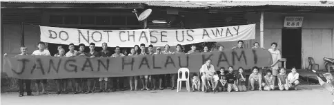  ??  ?? Sim (standing, eighth right) and the other residents of Trusan with their banners asking the authoritie­s not to chase them away after being served with notice to demolish their houses.