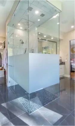  ??  ?? The ensuite hosts a luxurious, curbless steam shower with 10mm glass on three sides and privacy glazing. Multiple, polished nickel, wall mounted fixtures and a Pacific Beach pebble mosaic floor in Obsidian Black, add texture and shine.