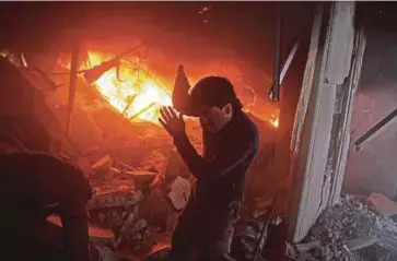  ?? - AFP ?? SEORANG lelaki mencari mangsa di dalam bangunan
yang terbakar susulan serangan udara tentera kerajaan di Douma, timur
Ghouta.