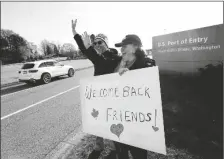  ?? ELAINE THOMPSON/AP ?? DUAL U.S.-CANADIAN CITIZEN TRAYSI SPRING (right) and her American husband Tom Bakken hold a homemade sign to welcome people heading into the U.S. from Canada on Monday in Blaine, Wash.