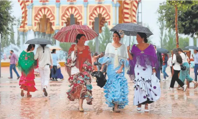  ?? // VALERIO MERINO ?? Varias jóvenes ataviadas de gitana con paraguas en el primer sábado de Feria en pleno aguacero en El Arenal