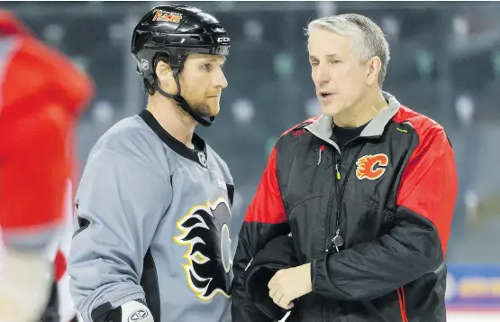  ?? LYLE ASPINALL/ POSTMEDIA NETWORK ?? Flames defenceman Dennis Wideman chats with coach Bob Hartley during practice in Calgary, his time skating with the team since his suspension. .