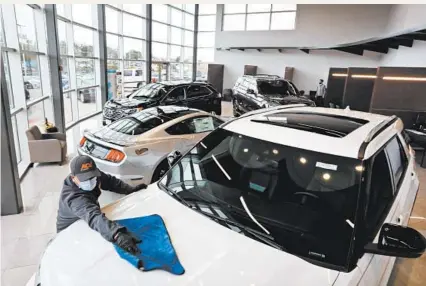  ?? ANTONIO PEREZ/CHICAGO TRIBUNE ?? Employee Alberto Hernandez touches up a new Ford Explorer on Thursday at Packey Webb Ford in Downers Grove.