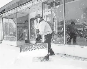  ?? JOSHUA A. BICKEL/ USA TODAY NETWORK ?? Mason Spohn shovels snow off a sidewalk Tuesday in Columbus, Ohio. Franklin County schools canceled remote and in- person classes after a storm dropped 3 to 4 inches of snow in the area.