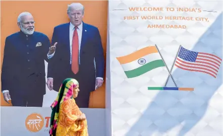  ?? PTI ?? A woman walks past a billboard featuring Prime Minister Narendra Modi and US President Donald Trump, ahead of latter’s maiden visit to India, in Ahmedabad on Sunday. —