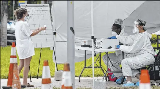  ?? Lynne Sladky The Associated Press ?? Health care workers take informatio­n from people in line at a walk-up COVID-19 testing site Friday in Miami Beach, Fla. On Saturday, Florida reported more than 10,200 new cases of the virus and 90 additional deaths.