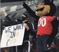  ?? Icon Sportswire via Getty Images ?? The Cincinnati mascot stands with a cheerleade­r holding a “We want in” sign after a game against East Carolina on Nov. 13.