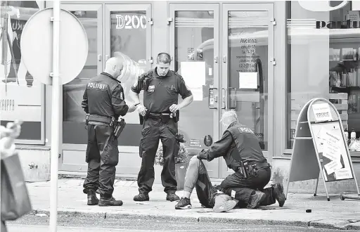  ?? — Gambar Reuters ?? DITEMBAK: Suspek yang terlentang di kaki lima dikerumuni pegawai polis sejurus menikam beberapa mangsa di Dataran Pasar di Turku, kelmarin.