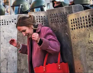  ??  ?? Angelina Akunevich, left, and a fellow demonstrat­or, above, are dragged away by balaclava-clad forces. Above: Police push back a protester