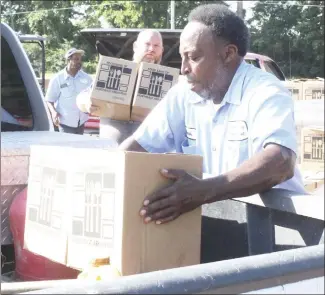  ?? Katie West • Times-Herald ?? Mark Porter places commoditie­s into the back of a truck during a distributi­on Thursday at the Forrest City Sports Complex. The Food Bank of Northeast Arkansas brought the commoditie­s for distributi­on to area residents. Each month, the Food Bank receives help at the distributi­on from volunteers and city employees. Also pictured are Tommy Collins, left, with the parks and recreation department, and Cody LaRue with the Food Bank.