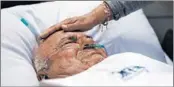  ?? HUSSEIN MALLA/AP ?? A relative comforts a patient this month at Family Medical Center, a private hospital facing a financial crisis, in Majdalaiya, Lebanon. The country has reported 43 virus deaths.