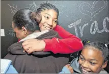  ?? ANDY SHARP / FOR AMERICAN-STATESMAN ?? Delashai Clark, 14, hugs her mom, Jamie Yancy, in their newly redone home in Round Rock as 8-year-old Nina Cousins smiles. The wall behind them is painted with chalkboard paint, and the children’s names are all written on it.