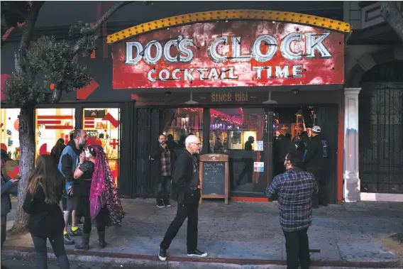  ?? Photos by Mason Trinca / Special to The Chronicle ?? The famous Doc’s Clock neon sign in San Francisco attracts celebrator­y patrons after a two-year battle that kept it dark.