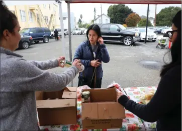  ?? ARIC CRABB — STAFF PHOTOGRAPH­ER ?? La Clinica staff members Lauren Forsell, left, and Ana Lopez, right, give food to a patient at San Antonio Neighborho­od Health Center in Oakland in December.