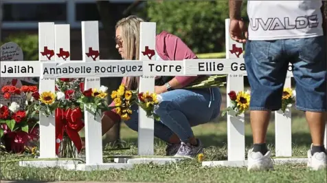  ?? Kin Man Hui/The San Antonio Express-News via AP ?? A mourner places flowers by each of the wooden crosses Thursday at a memorial site for the victims of the Robb Elementary School shooting in Uvalde, Texas.