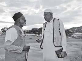  ?? DAVID MCFADDEN AP ?? In this photo taken May 3, 2013, Yasin Abu Bakr, right, who led a small army that stormed Trinidad & Tobago’s parliament in 1990, speaks with a fellow member of his group, Jamaat al Muslimeen, at their compound in Port-of-Spain, Trinidad. Abu Bakr, never convicted of any charges, presided over a mosque and school complex in the country’s capital and shared time among his four wives, the maximum Islam allows.