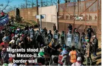  ??  ?? Migrants stood at the Mexico-U.S.
border wall