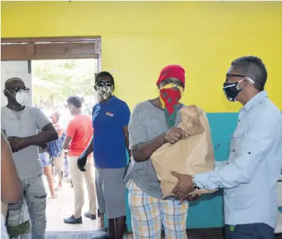  ??  ?? Negril Chamber of Commerce President Richard Wallace (right) hands a care package to a resident at the Negril Community Centre on Thursday.