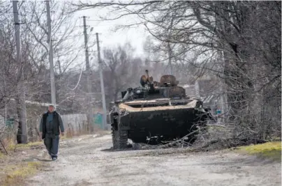  ?? AP PHOTO/RODRIGO ABD ?? A villager walks next to a destroyed Russian tank Monday near the front line in Brovary, in the outskirts of Kyiv, Ukraine.