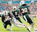  ?? MIKE EHRMANN/GETTY IMAGES ?? Hurricanes cornerback Michael Jackson picks off a pass by Syracuse quarterbac­k Eric Dungey during Saturday’s game. The ’Canes had four first-half intercepti­ons.