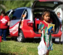  ?? NWA Democrat-Gazette/JASON IVESTER ?? Alyssa John, a rising second-grader at Sonora Elementary, heads for home with her book selections and snacks from the school’s mobile library stopped in The Commons neighborho­od. Many of the school’s students have no access the public library for books...