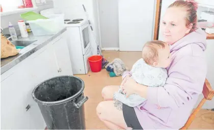  ?? Photo / Warren Buckland ?? Vannessa Pye, with then 4-month-old Carter, in the wet kitchen. Water leaked from the kitchen ceiling in the Kainga Ora house in Napier, but they've since been given a different home in Hastings.