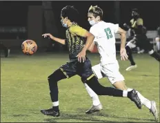  ??  ?? ABOVE: YUMA CATHOLIC’S SAUL MARTINEZ (left) races toward the Avondale-St. John Paul II Catholic goal with the Lions’ Benji Avila in pursuit during the first half of Thursday night’s game. BELOW: AVONDALE-ST. JOHN PAUL II CATHOLIC GOAL KEEPER CARLOS ENCINAS (center) tries but can’t stop Yuma Catholic’s Saul Martinez (16) from heading the ball into the goal for the Shamrocks’ first score at the 32-minute mark in the first half. Also trying to defend is St. John Paul II’s Nicholas Delgado (23).