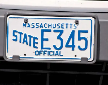  ?? HERALD PHOTOS BY RYAN MCBRIDE ?? COST CONCERNS: University of Massachuse­tts Boston vehicles are seen in one of the school’s parking lots, top, yesterday, with the license plate of one of the UMass Boston vehicles seen above.