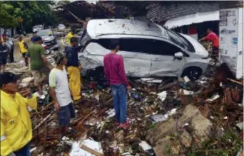  ?? AP PHOTO ?? People inspect the wreckage of a car swept away by a tsunami in Carita, Indonesia, Sunday, Dec. 23, 2018.