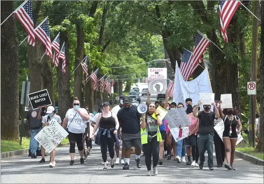  ?? PETE BANNAN - MEDIANEWS GROUP ?? Black Lives Matter protesters march between the flags along Knowles Avenue in Glenolden Park on Saturday.