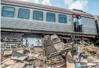  ?? AFP ?? Passengers on an incoming train, which slowed down at the scene of the fatal rail crash, looks at the wreckage lying in the Khorshid area near Alexandria . —