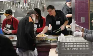  ?? JOHN RENNISON PHOTOS THE HAMILTON SPECTATOR ?? Volunteers from Notre Dame Church serve dinner at Good Shepherd emergency men's shelter. About 450 to 500 meals are served each day with the help of up to a dozen volunteers.