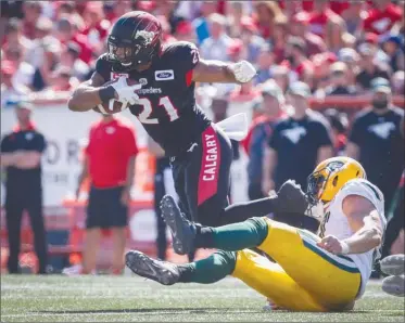  ?? The Canadian Press ?? Calgary Stampeders running back Anthony Woodson, left, dodges a tackle attempt by Edmonton Eskimos defensive end John Chick during second-half CFL action in Calgary on Monday.