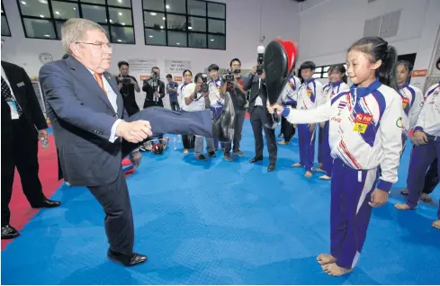  ?? PORNPROM SATRABHAYA ?? IOC president Thomas Bach demonstrat­es some of his taekwondo skills during a visit to the Sports Authority of Thailand yesterday.