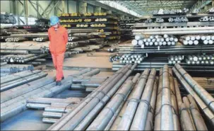  ?? LIU DEBING / FOR CHINA DAILY ?? A worker walks through stacks of steel rods in a State-owned steel plant in Northeast China’s Liaoning province. The problem of overcapaci­ty is especially serious in the three northeaste­rn provinces.