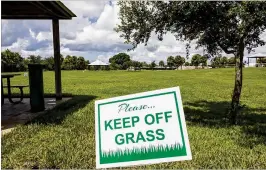  ?? RICHARD GRAULICH / THE PALM BEACH POST ?? On Monday, signs warn that new turf has been installed at North Palm Beach’s Anchorage Park. The $1 million project will include improvemen­ts to the small dog park, walking trails and baseball field.