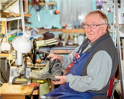  ?? VANESSA LAURIE/STUFF ?? David Deacon has been in the shoe business for more than two decades, fixing shoes, like this work boot, on an old Singer sewing machine and other tools.