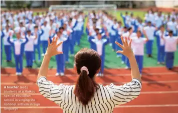  ?? ?? A teacher leads students at a Haikou special education school in singing the national anthem in sign language